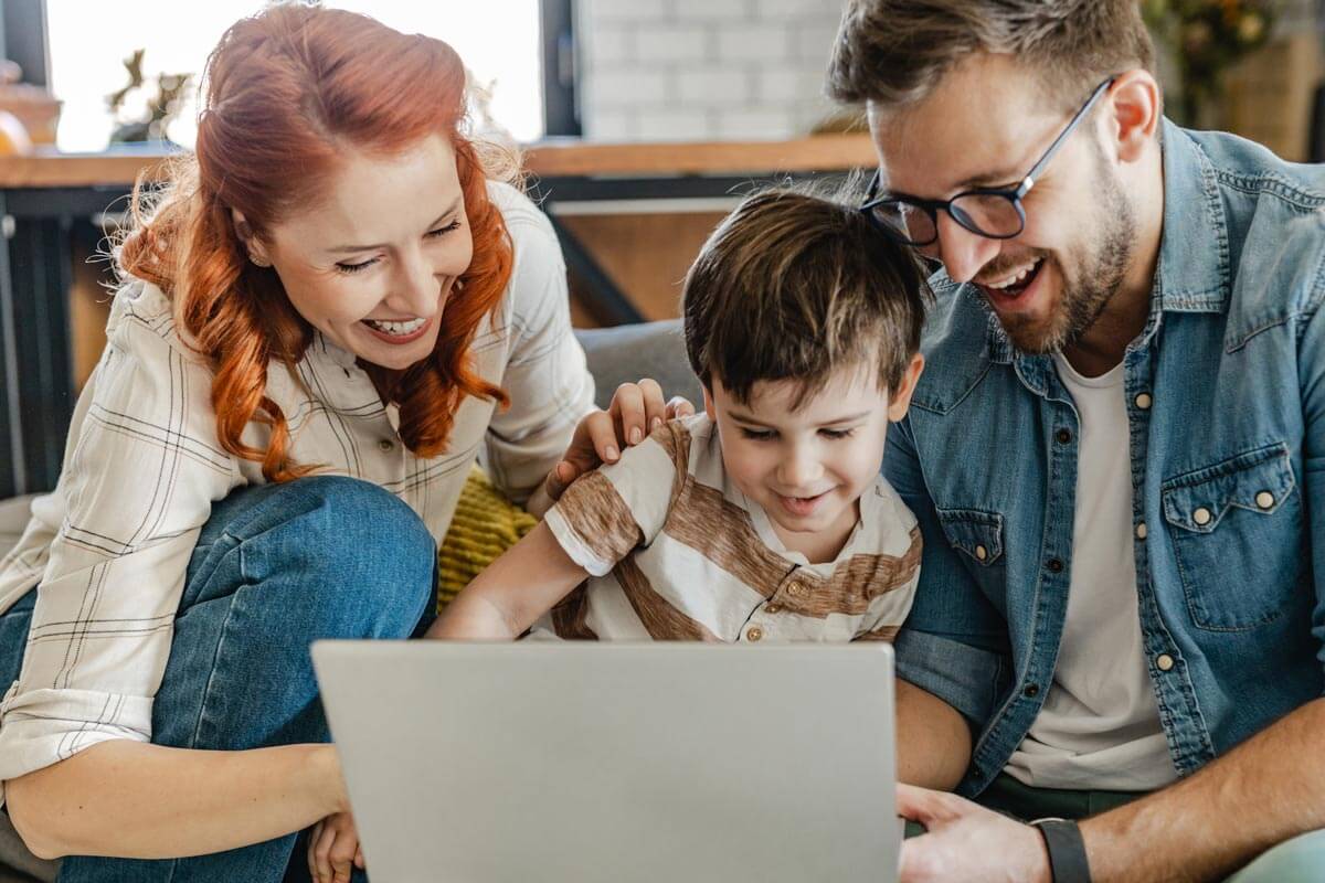 mother and father smiling and looking at laptop with son